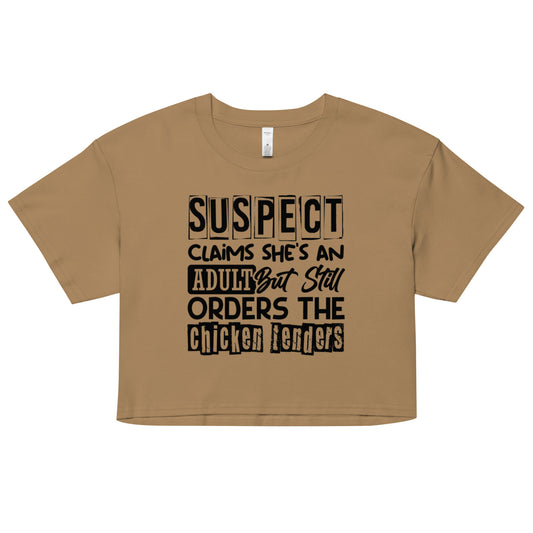 crop top with black text “Suspect Claims She’s an Adult But Still Orders the Chicken Tenders”