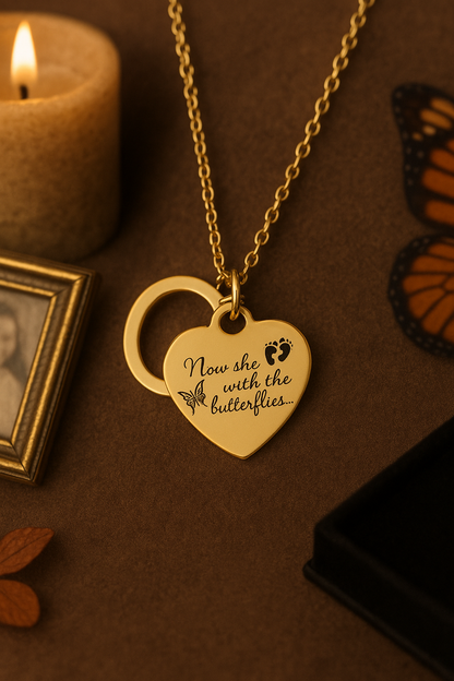 Gold heart-shaped necklace with engraved text on a brown surface with a candle and butterfly decorations.