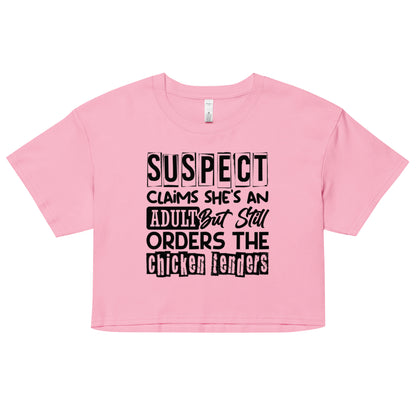 crop top with black text “Suspect Claims She’s an Adult But Still Orders the Chicken Tenders