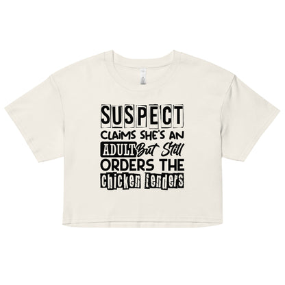 crop top with black text “Suspect Claims She’s an Adult But Still Orders the Chicken Tenders”