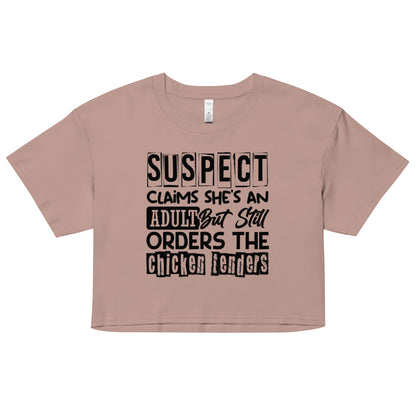 crop top with black text “Suspect Claims She’s an Adult But Still Orders the Chicken Tenders”